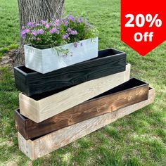 three wooden planters stacked on top of each other in the grass near a tree