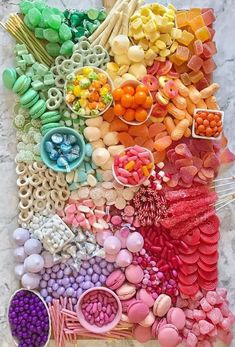 an array of different colored candies on a marble surface with spoons and forks