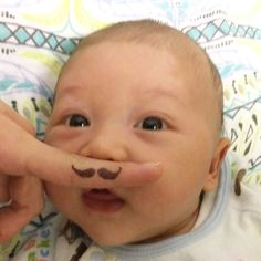 a baby with a fake mustache on his nose