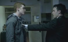 two young men standing next to each other in a room with cabinets and cupboards