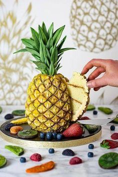 a pineapple cut in half on top of a plate with fruit and vegetables around it