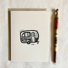 a card with a drawing of a camper on it next to a pen