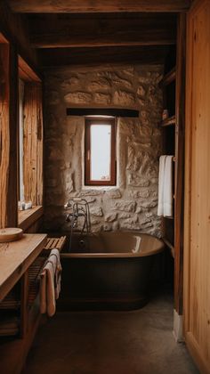 an old fashioned bathtub in a rustic bathroom with stone walls and floor, along with a window