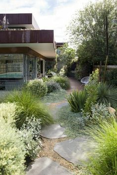 a house that has some plants in front of it and grass on the ground next to it