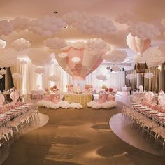 a banquet hall with tables and chairs covered in pink and white paper lanterns, balloons and other decorations