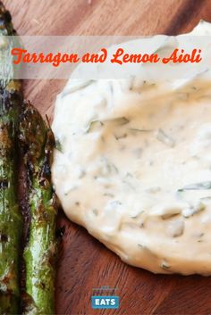 some asparagus on a wooden cutting board with dip