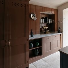 a kitchen with brown cabinets and white marble counter tops, along with black vases