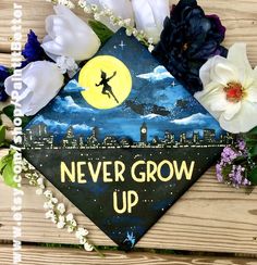 a graduation cap decorated with flowers and the words never grow up