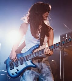 a woman holding a blue guitar on stage