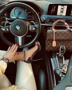 a woman sitting in the driver's seat of a car with her hand on the steering wheel