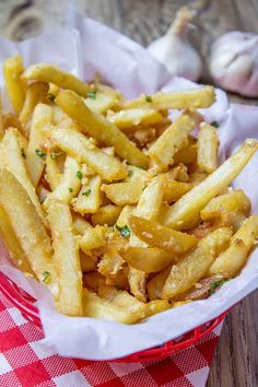 a basket filled with french fries on top of a red and white checkered table cloth