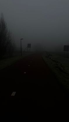 an empty road in the middle of a foggy field with signs on either side