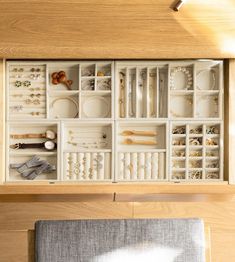 an open drawer with jewelry and other items in it on top of a wooden table