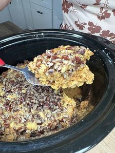 a person scooping some food out of a crock pot