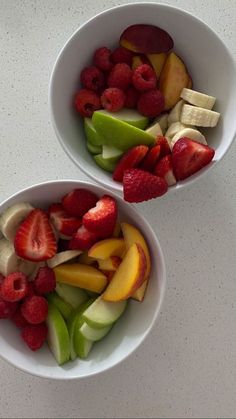 two white bowls filled with fruit on top of a table