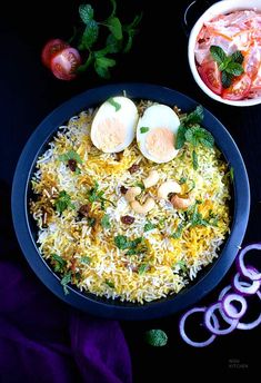 an egg and rice dish served in a bowl with onion rings on the side next to it