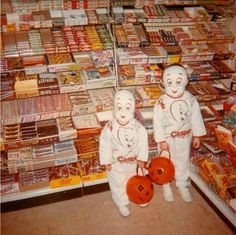 two children in white costumes standing next to each other with pumpkins on their hands