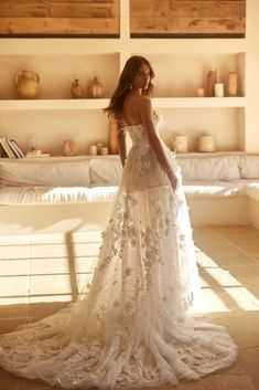 a woman in a white wedding dress is standing near shelves with vases on it