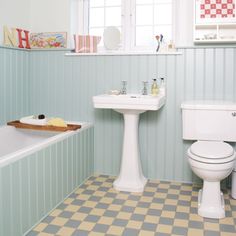 a white toilet sitting next to a bath tub and sink in a bathroom under a window