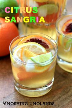 two glasses filled with citrus sangria and limes on top of a wooden table