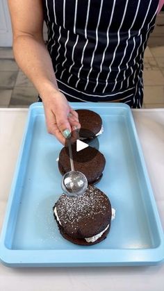 a woman in an apron is decorating chocolate cookies