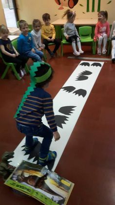 a young boy riding a skateboard on top of a white board in front of children