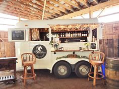 an ice cream truck parked in a barn with two wooden stools next to it