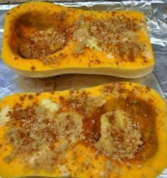 two squash halves covered in seasoning sitting on top of foil lined baking pans