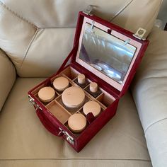 This is a travel vintage vanity box. Made circa 1940 or 1950 by Asprey in London of a dark red suede outer with a pale pink silk lining. There is a rectangular mirror slightly distressed at the back which can be removed to create a freestanding mirror. The front lifts to reveal 10 sections. 6 of these are part of a top tray. There are 2 glass bottles with cork lined screw on lids and inner Bakelite screw on droppers. It has glass cream/trinket pots with card lined screw on cream enamel lids. The outer lid has the monogram S. There are 2 clip closures which are released and open by squeezing and releasing side clips.  The outer suede is in very good condition. The inner silk has age related spotting and discolouration. The enamel lids are worn. There are no keys. 21.5 x 17.5 x 12cm We have 1940s Vanity, Makeup Vanity Box, Freestanding Mirror, Travel Vanity, Freestanding Mirrors, Vintage Compact, Gloves Vintage, Wooden Bag, Glass Bottles With Corks