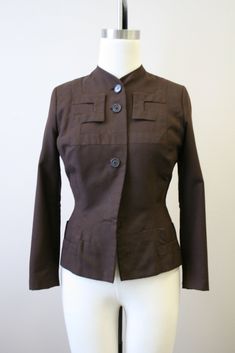 "Description: 1940s brown wool jacket, with an amazing geometric appliqued design. Button front with long sleeves. It has a hook and eye closure at the top button. Shaped, nipped waist with padded shoulders. Fully lined. Condition: In fair condition, with no stains. It has scattered moth holes over the body, sleeves, and cuffs (see the photos). It is missing two front buttons, although the buttons are very simple and would be fairly easy to replace. Designer: Adrian Stated Size: n/a Measurements Brown Stand Collar Blazer With Buttons, Brown Stand Collar Blazer With Button Closure, Brown Blazer With Stand Collar And Buttons, Brown Blazer With Button Closure And Stand Collar, Brown Single Breasted Blazer With Stand Collar, Fitted Brown Blazer With Hidden Button Closure, Vintage Stand Collar Blazer For Work, Vintage Blazer With Stand Collar For Work, Fitted Brown Outerwear With Hidden Button Closure