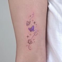 a woman with a tattoo on her arm that has butterflies and stars flying in the sky