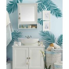 a bathroom with palm leaves on the wall and a white sink in front of it