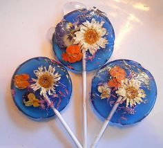 three lollipops decorated with flowers and daisies