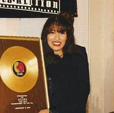 a woman holding up an award plaque in front of a sign that reads, star