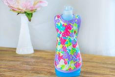 a water bottle sitting on top of a wooden table next to a vase with flowers