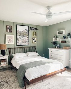 a bedroom with green walls and white furniture