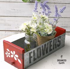 two mason jars filled with flowers sitting on top of a wooden box that says flowers