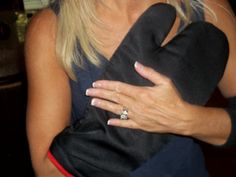 a woman holding a black dog in her arms and wearing a ring on it's finger