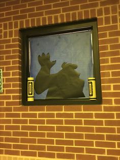 the reflection of a frog in a window on a brick wall with a green frame