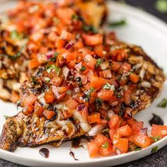 grilled chicken with tomatoes and onions on a white plate