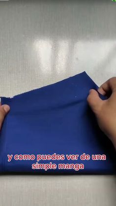 the person is making something out of blue paper with their hands on top of it