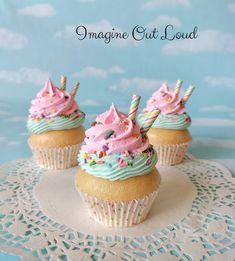 three cupcakes with pink frosting and sprinkles on a doily