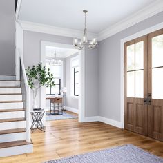 a living room filled with furniture next to a stair case and wooden door leading up to the second floor