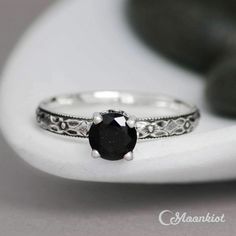 a black diamond ring sitting on top of a white rock