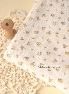 a white doily sitting on top of a table next to a piece of cloth