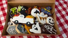 a box filled with decorated cookies on top of a red and white checkered table cloth