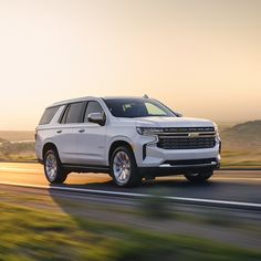 a white chevy suburban is driving down the road