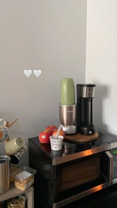 a microwave oven sitting on top of a counter next to an apple and coffee maker