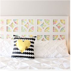 a white bed topped with a black and white pillow next to a wall covered in pictures