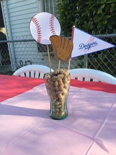 a glass vase filled with nuts and baseballs on top of a pink table cloth